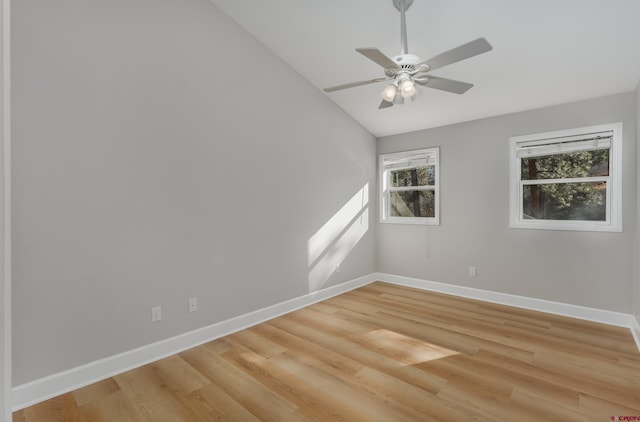 unfurnished room with vaulted ceiling, a ceiling fan, baseboards, and light wood-type flooring