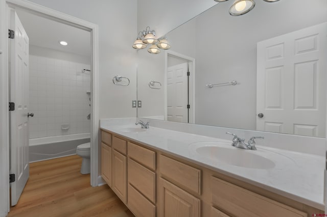 bathroom featuring a sink, toilet, wood finished floors, and double vanity