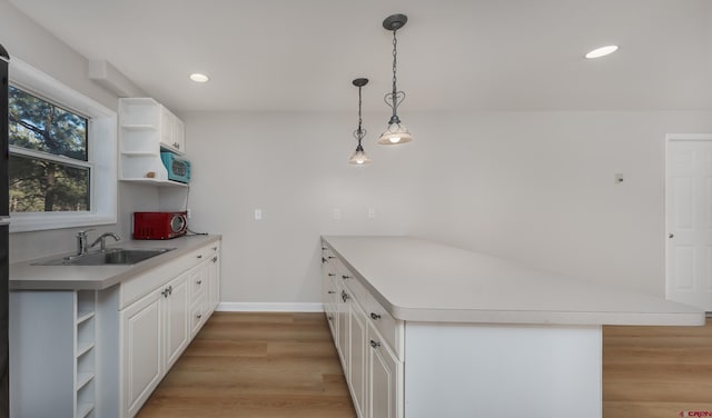 kitchen with open shelves, a peninsula, a sink, light wood-style floors, and white cabinetry