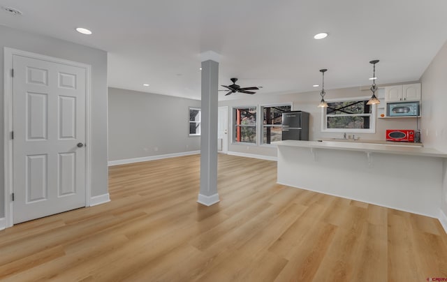 unfurnished living room featuring a sink, baseboards, recessed lighting, and light wood finished floors