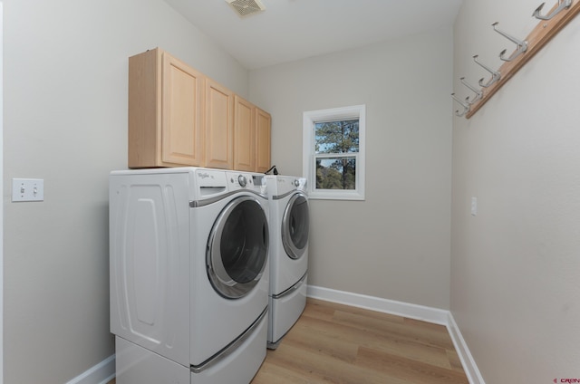 washroom with cabinet space, light wood-style flooring, separate washer and dryer, and baseboards