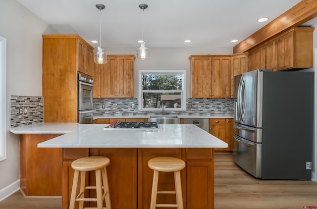 kitchen featuring light wood-type flooring, a sink, light stone counters, appliances with stainless steel finishes, and brown cabinetry