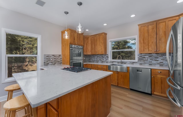 kitchen with a breakfast bar, brown cabinets, a peninsula, stainless steel appliances, and a sink