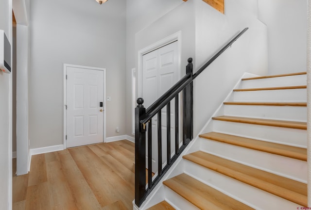 entryway featuring stairway, wood finished floors, baseboards, and a towering ceiling