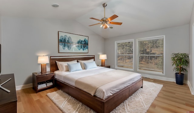 bedroom featuring light wood finished floors, ceiling fan, baseboards, and vaulted ceiling