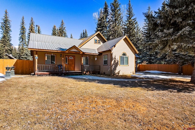 view of front of home featuring a porch, fence, a front lawn, and metal roof