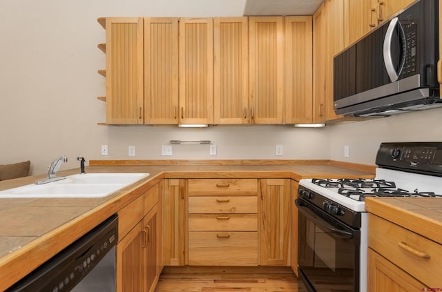 kitchen with light brown cabinets, open shelves, a sink, tile counters, and appliances with stainless steel finishes