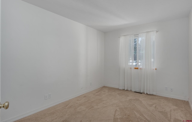 unfurnished room with light carpet and baseboards