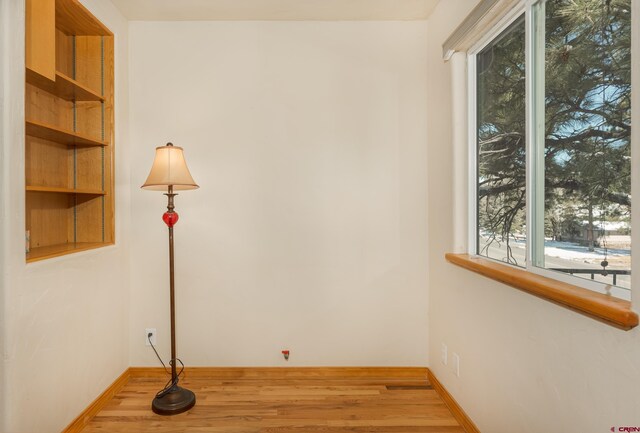 spare room with baseboards and wood finished floors