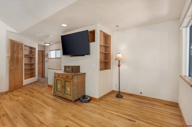 living area featuring built in features, baseboards, and light wood-type flooring