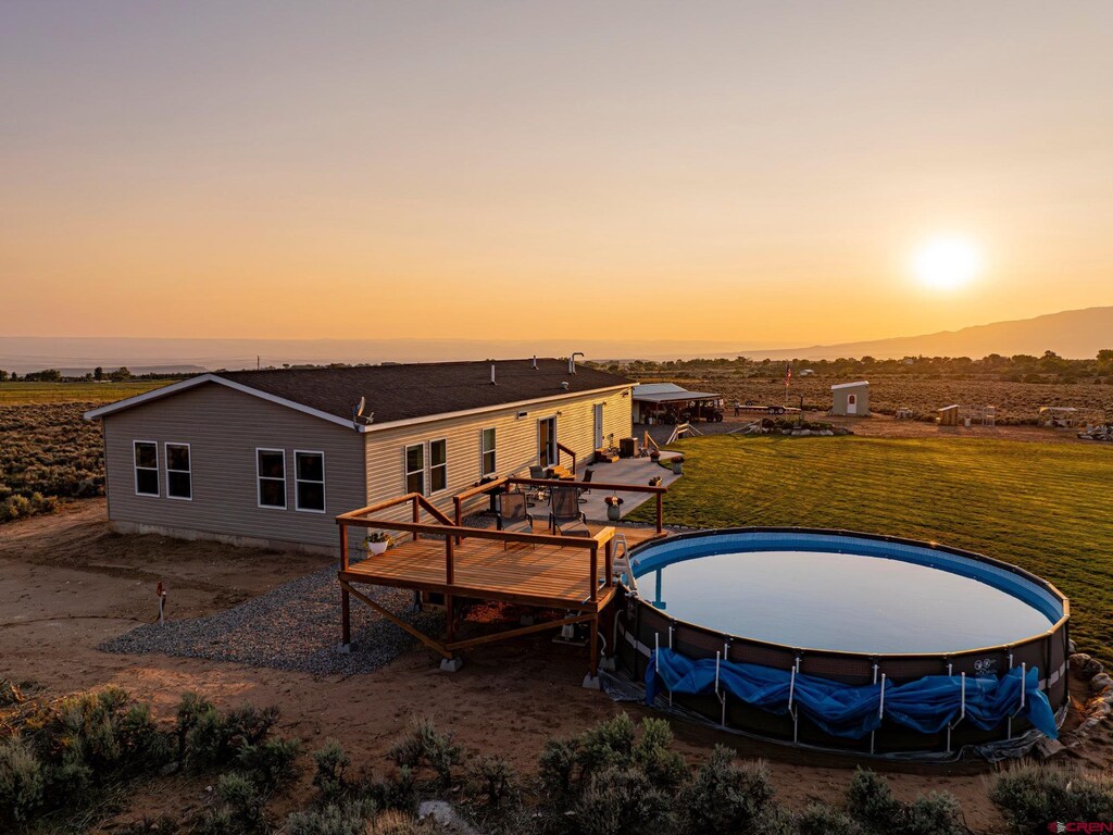 back of property at dusk featuring a deck and a lawn