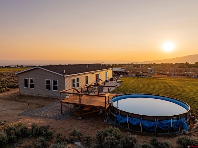 back of property at dusk featuring a deck and a lawn