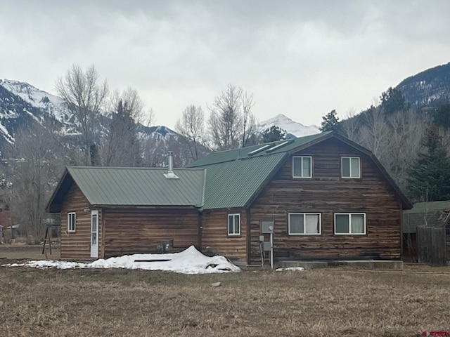 rear view of house with a mountain view, a gambrel roof, a lawn, and metal roof