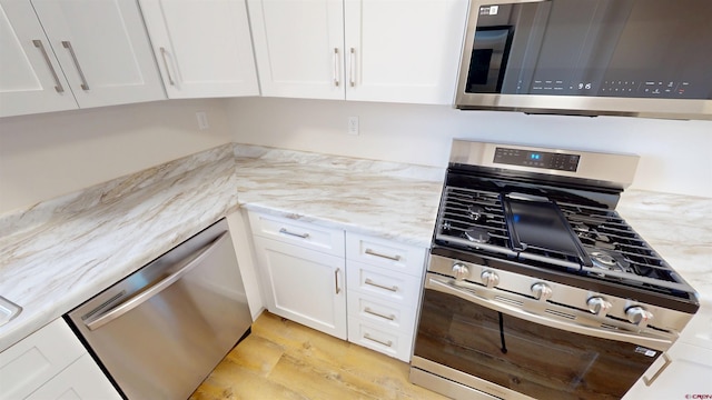 3601 Tinker Dr, Aztec, NM 87410 - kitchen with light stone counters, light wood-style flooring, appliances with stainless steel finishes, and white cabinets