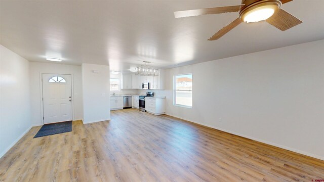 3601 Tinker Dr, Aztec, NM 87410 - unfurnished living room with baseboards, ceiling fan with notable chandelier, and light wood finished floors