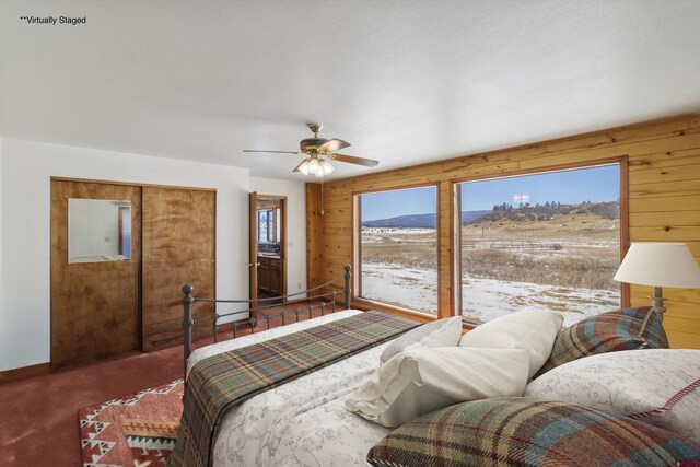 bedroom featuring multiple windows, a ceiling fan, wood walls, and access to outside