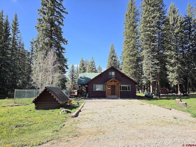 view of front of home with gravel driveway, a front lawn, and metal roof