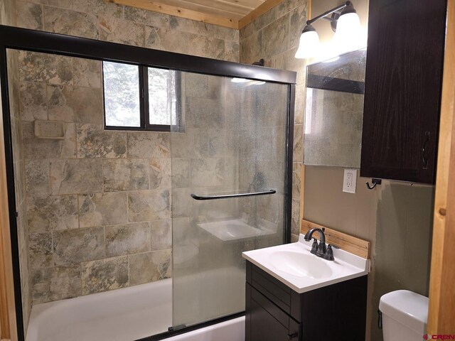 bathroom with combined bath / shower with glass door, toilet, and vanity