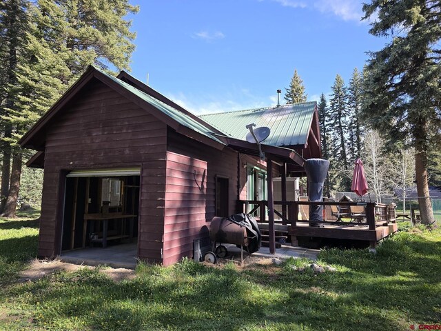 view of home's exterior featuring a deck, a lawn, a garage, and metal roof