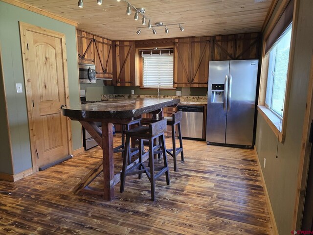 kitchen with wood ceiling, stainless steel appliances, brown cabinetry, and wood finished floors