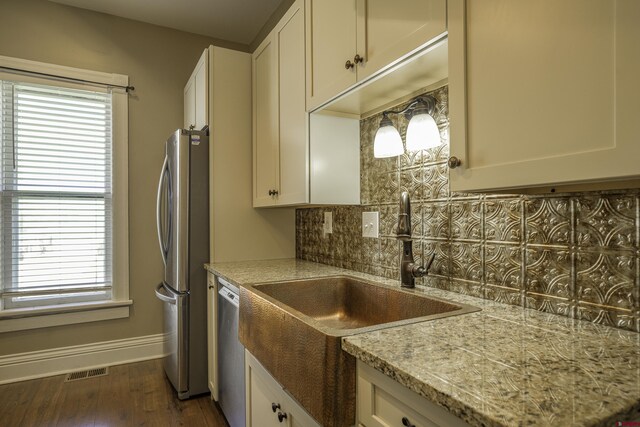 1003 San Juan St, Trinidad, CO 81082 - kitchen with stainless steel appliances, decorative backsplash, a sink, white cabinets, and baseboards