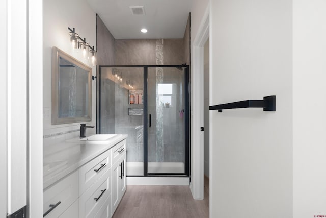 2305 Mountain Pines Dr, Montrose, CO 81401 - bathroom with visible vents, a shower stall, double vanity, wood finished floors, and a sink