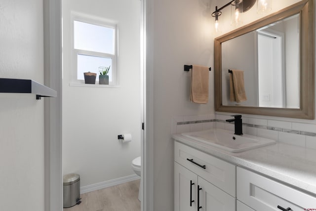 2305 Mountain Pines Dr, Montrose, CO 81401 - bathroom featuring toilet, vanity, tasteful backsplash, wood finished floors, and baseboards