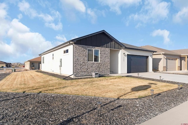 2305 Mountain Pines Dr, Montrose, CO 81401 - view of front facade with concrete driveway, stone siding, board and batten siding, a front yard, and a garage
