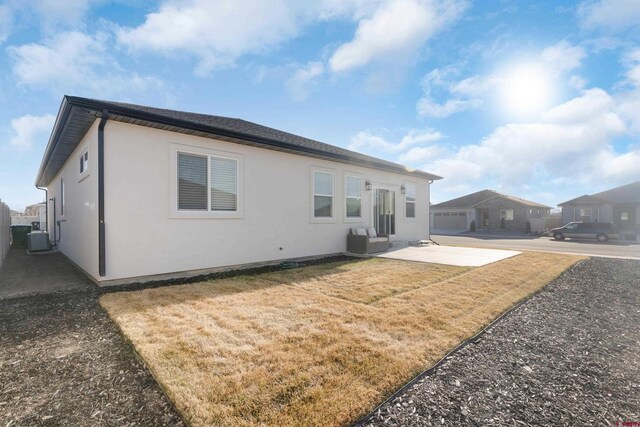 2305 Mountain Pines Dr, Montrose, CO 81401 - back of house with cooling unit, stucco siding, a patio area, and a lawn