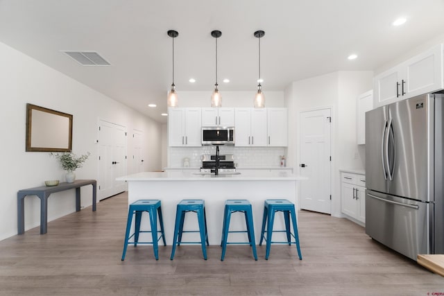 2305 Mountain Pines Dr, Montrose, CO 81401 - kitchen with visible vents, a breakfast bar, white cabinetry, and stainless steel appliances