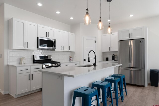 2305 Mountain Pines Dr, Montrose, CO 81401 - kitchen with white cabinetry, light wood finished floors, a sink, and appliances with stainless steel finishes