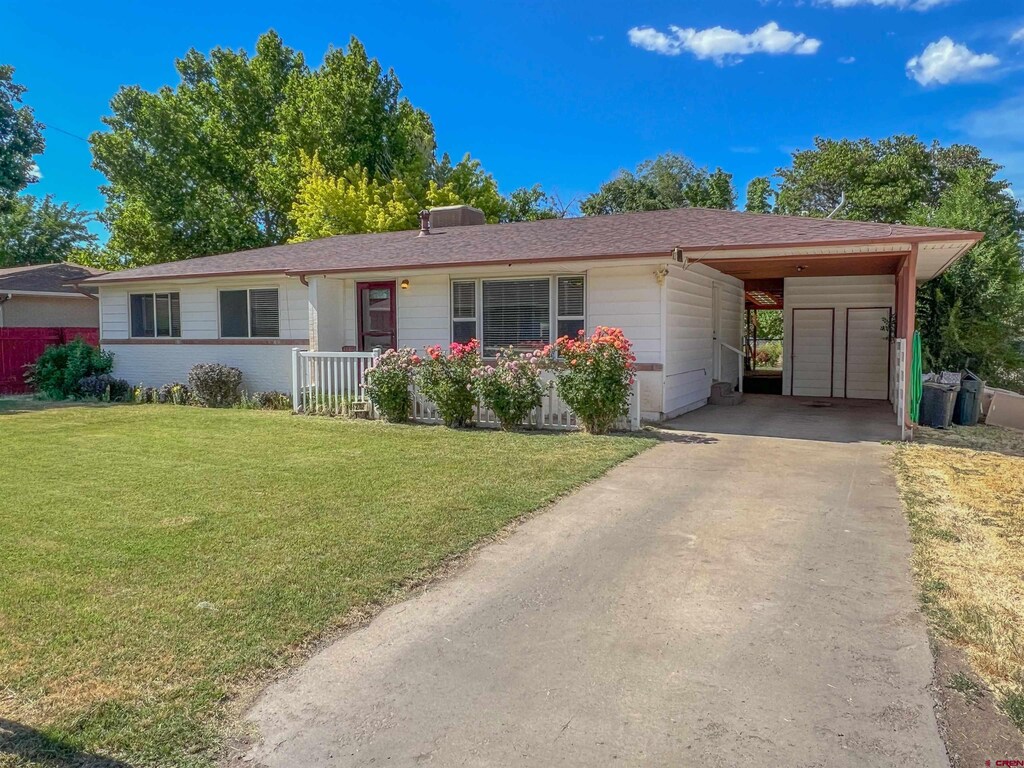 ranch-style house with driveway, a front yard, and a carport