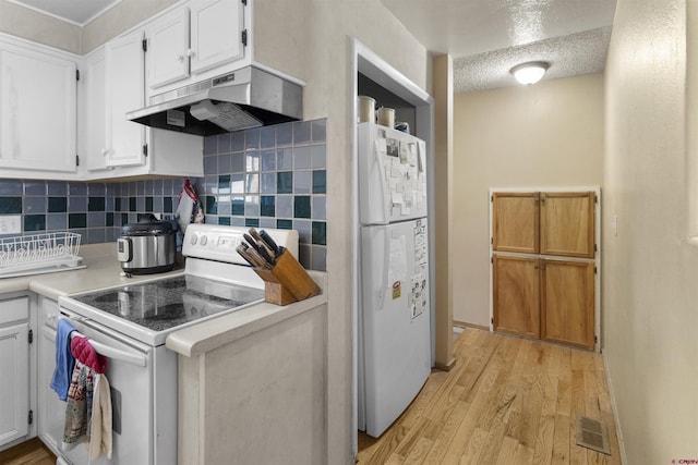 801 S Nevada Ave, Montrose, CO 81401 - kitchen with white cabinetry, under cabinet range hood, white appliances, visible vents, and light wood-style floors