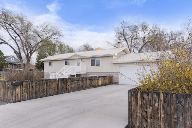801 S Nevada Ave, Montrose, CO 81401 - view of front of house with metal roof, driveway, a fenced front yard, a garage, and a chimney