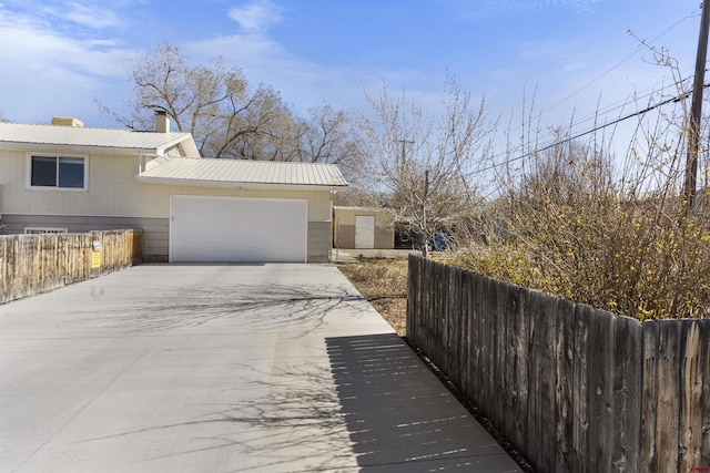 801 S Nevada Ave, Montrose, CO 81401 - view of home's exterior featuring concrete driveway, fence, metal roof, a garage, and a chimney