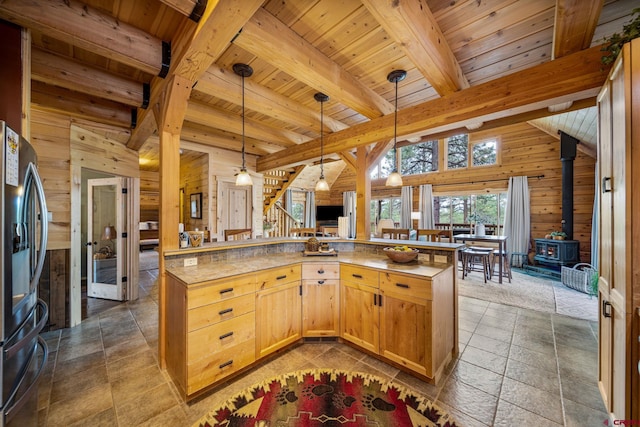 1838 Beaver Creek Dr, Bayfield, CO 81122 - kitchen with lofted ceiling with beams, wood walls, stainless steel fridge, a wood stove, and wood ceiling