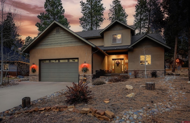 view of front facade featuring driveway, a shingled roof, a garage, and stone siding