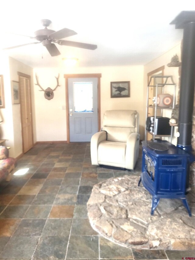 1435 Pine St, Norwood, CO 81423 - living area with stone finish floor, a wood stove, and a ceiling fan