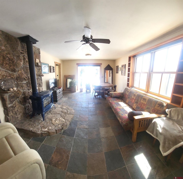 1435 Pine St, Norwood, CO 81423 - living area with stone tile floors, a wood stove, and a ceiling fan