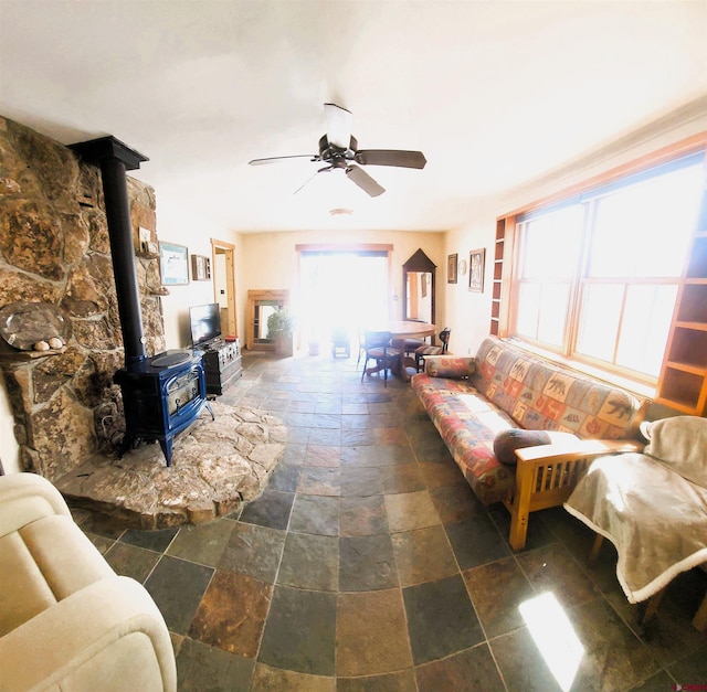 1435 Pine St, Norwood, CO 81423 - living room featuring stone tile floors, a wood stove, and a ceiling fan