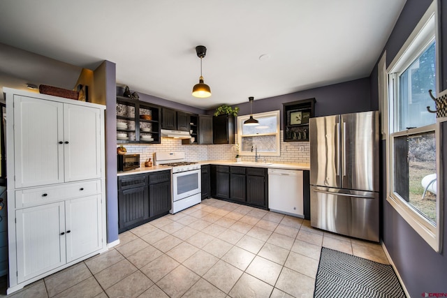 kitchen featuring a sink, light countertops, white appliances, and decorative backsplash