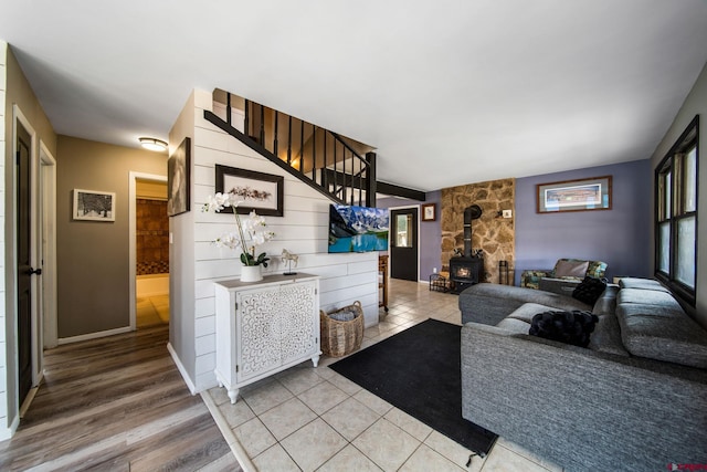 living area featuring a wood stove, light wood finished floors, and baseboards