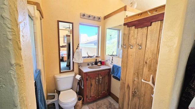 bathroom featuring a textured wall, vanity, and toilet
