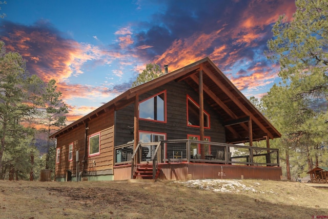 back of house at dusk featuring a deck
