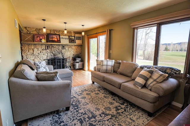 107 Shavano Dr Unit A1, Gunnison, CO 81230 - living room featuring a stone fireplace, a wealth of natural light, wood finished floors, and a textured ceiling