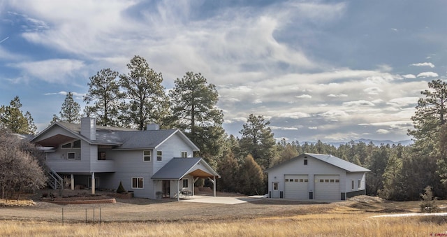 view of front of property with an outdoor structure, a patio, a garage, and a chimney