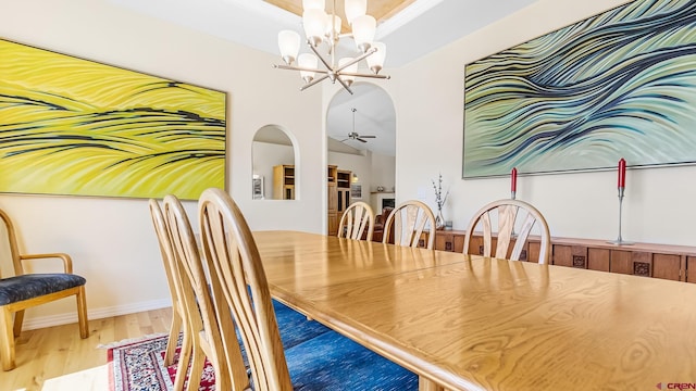 dining area featuring wood finished floors and ceiling fan with notable chandelier