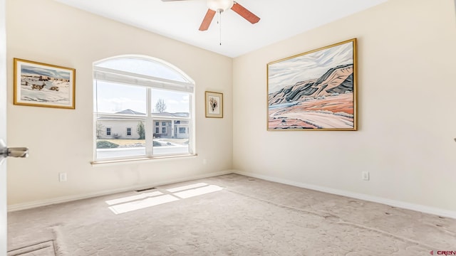 carpeted spare room featuring visible vents, baseboards, and ceiling fan