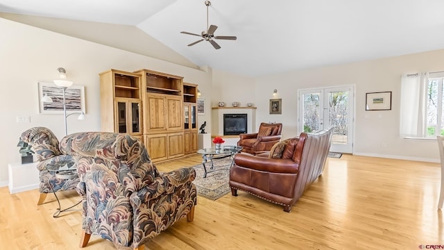 living area featuring light wood-style flooring, ceiling fan, baseboards, and lofted ceiling