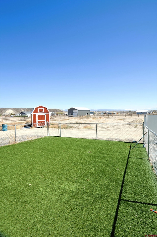 view of yard featuring an outdoor structure, fence, and a storage unit